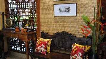 A traditional-style living room with a wooden sofa, a coffee table, and a decorative screen.