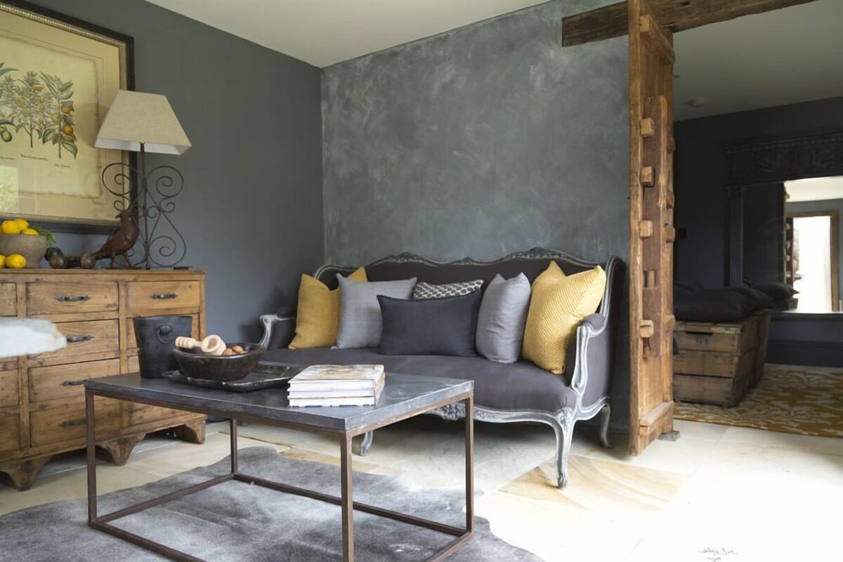 Una habitación con un sofá gris oscuro, un aparador de madera, una mesa de centro metálica e ilustración botánica enmarcada en la pared.