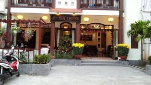 A building with a sign reading "NH TRUNG" and a Christmas tree in front. - Nhi Trung Hotel (Da Nang)