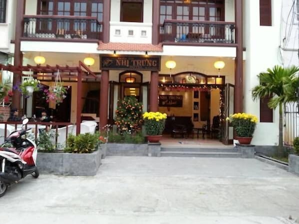 A building with a sign reading "NH TRUNG" and a Christmas tree in front. - Nhi Trung Hotel (Da Nang)