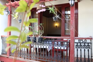 A balcony with wrought iron railings, potted plants, and hanging flower baskets. - Nhi Trung Hotel (Da Nang)