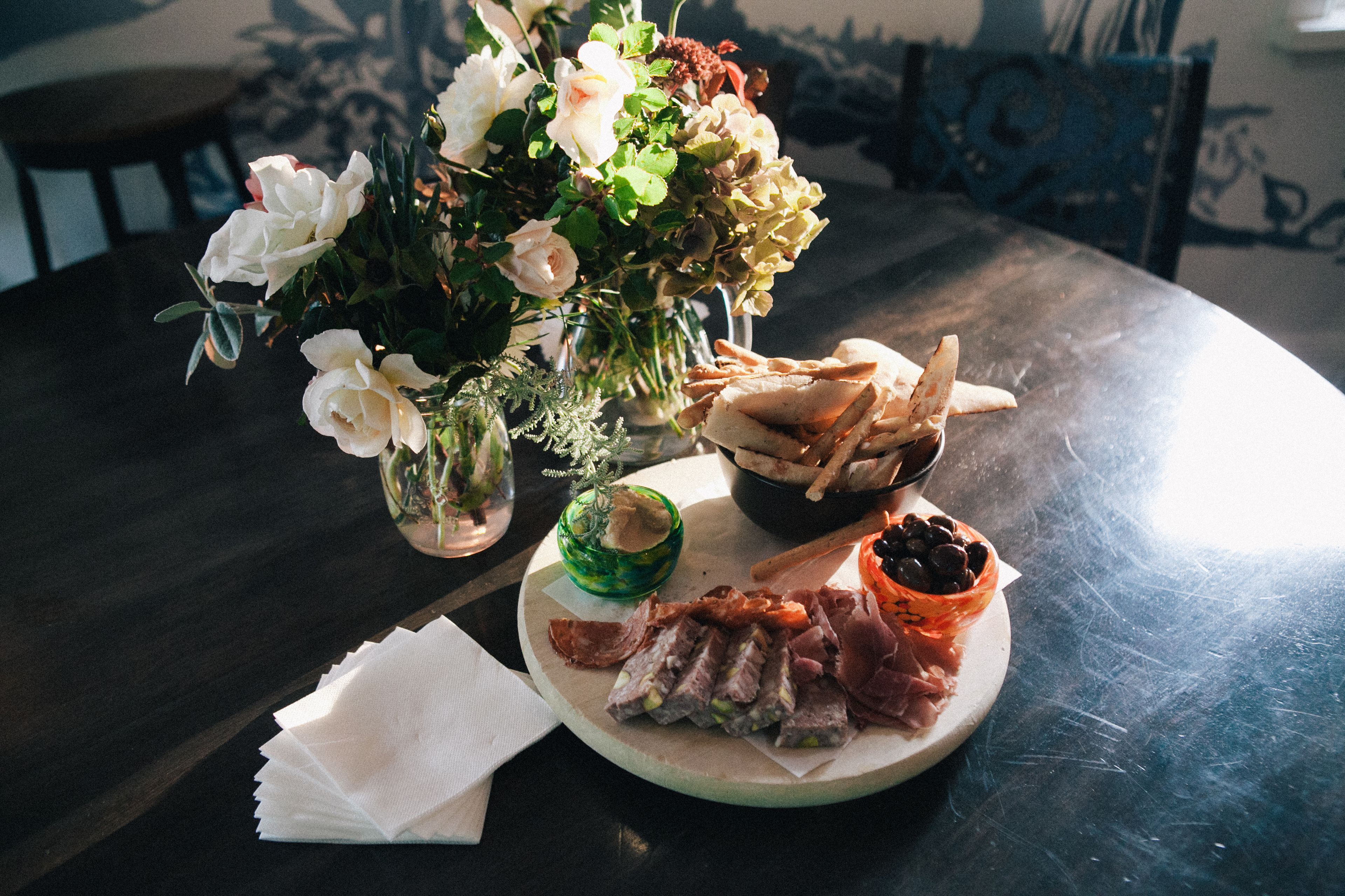 A dining table with a plate of food, a vase of flowers, and a napkin.