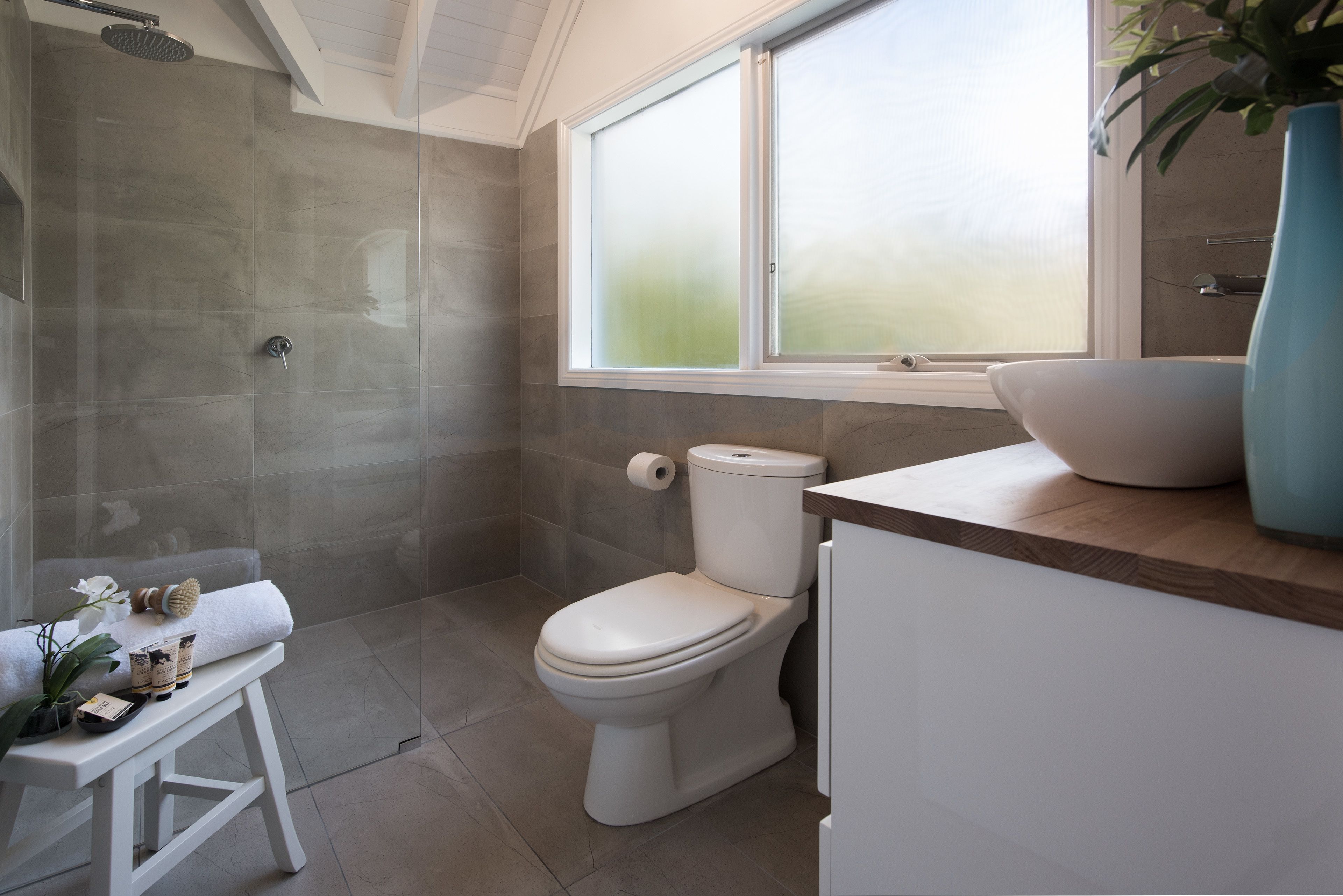 A modern bathroom with a shower, toilet, and sink.