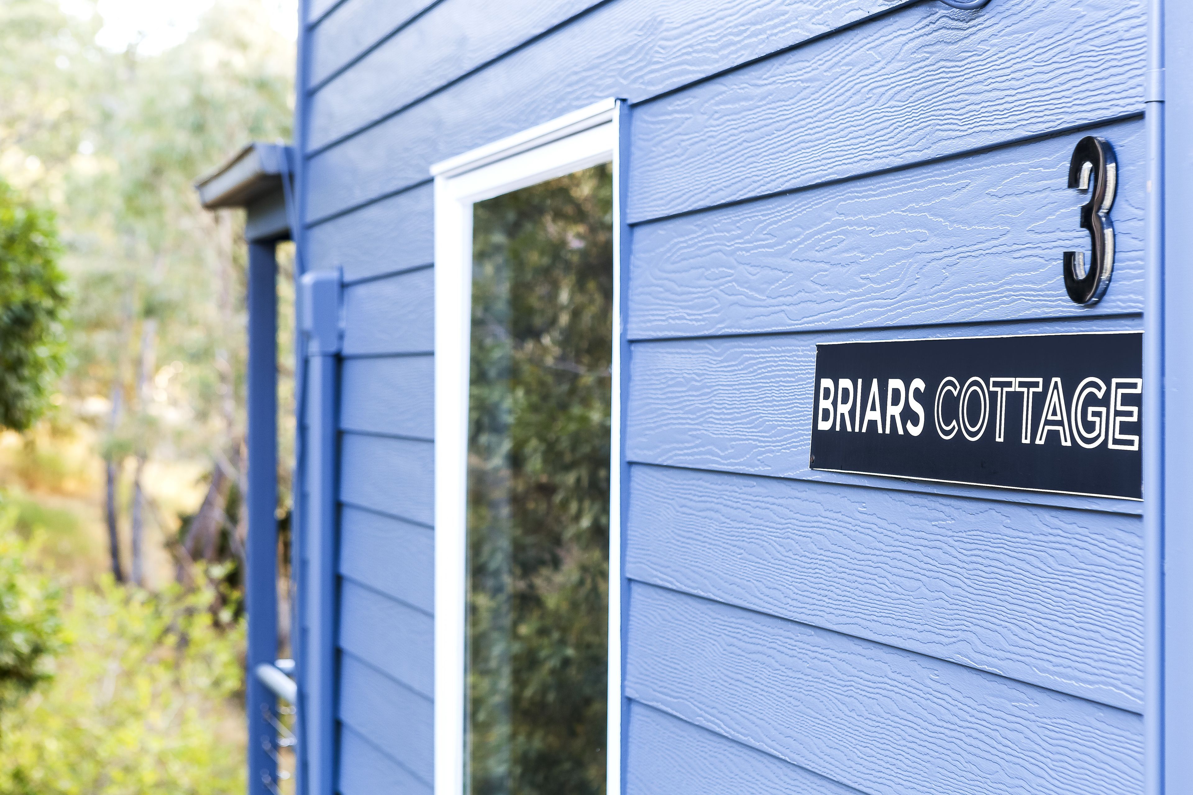 Una casa con un letrero que dice "Briars Cottage" y el número "3" en la puerta.