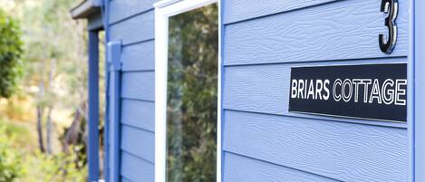 Una casa con un letrero que dice "Briars Cottage" y el número "3" en la puerta.