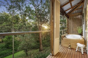 Una terraza de madera con un jacuzzi, un taburete pequeño y una botella de champán.