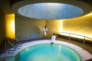 Una piscina con un muro de azulejos y un tragaluz circular arriba.