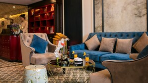 A modern living room with a blue sofa, a beige armchair, and a glass coffee table. - Golden Rooster Hotel (Hanoi)