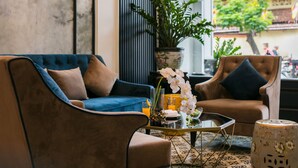 A living room with a blue sofa, two armchairs, a glass coffee table, and a potted plant. - Golden Rooster Hotel (Hanoi)