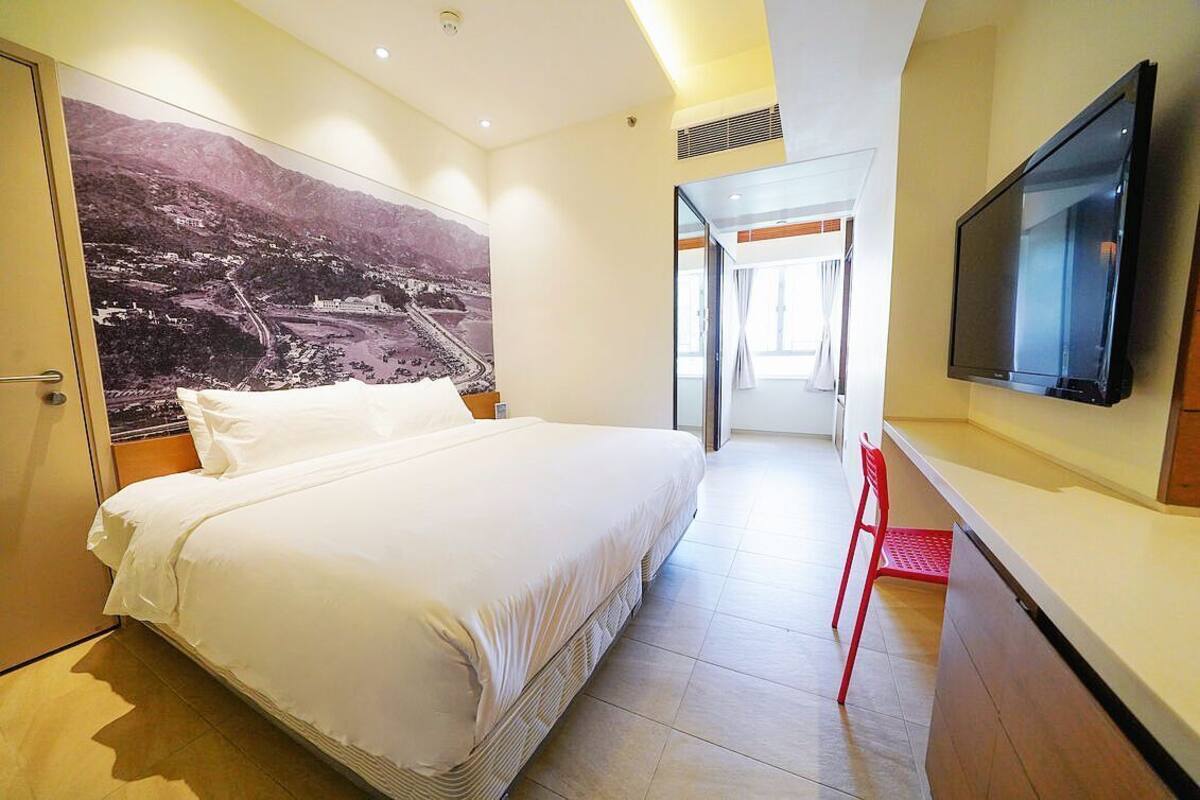 A hotel room with a large bed, a flat-screen TV, and a large wall mural.