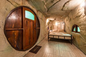 A room with a wooden wardrobe, a bed, and a small window.