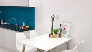 Une cuisine moderne avec une table et des chaises blanches, un pare-feu bleu et une petite plante en pot.