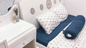 Une chambre à coucher avec un lit blanc, un oreiller bleu et une table de chevet blanche.