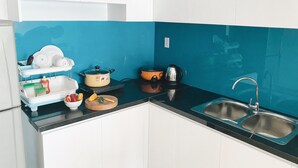 Une cuisine avec des meubles blancs, un plan de travail noir, un évier et divers appareils de cuisine.