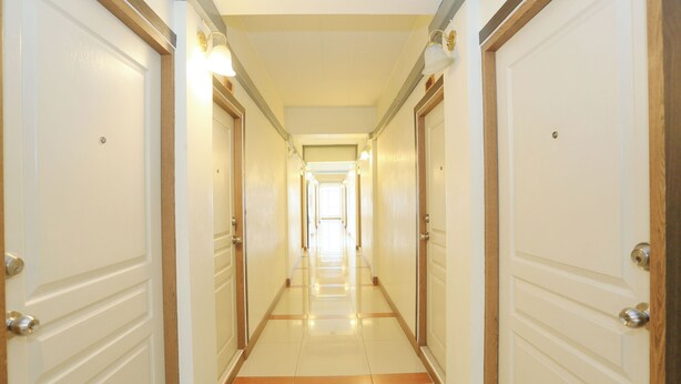 A hotel hallway with multiple doors, light fixtures, and a tiled floor. - SK Resort (Bangkok)
