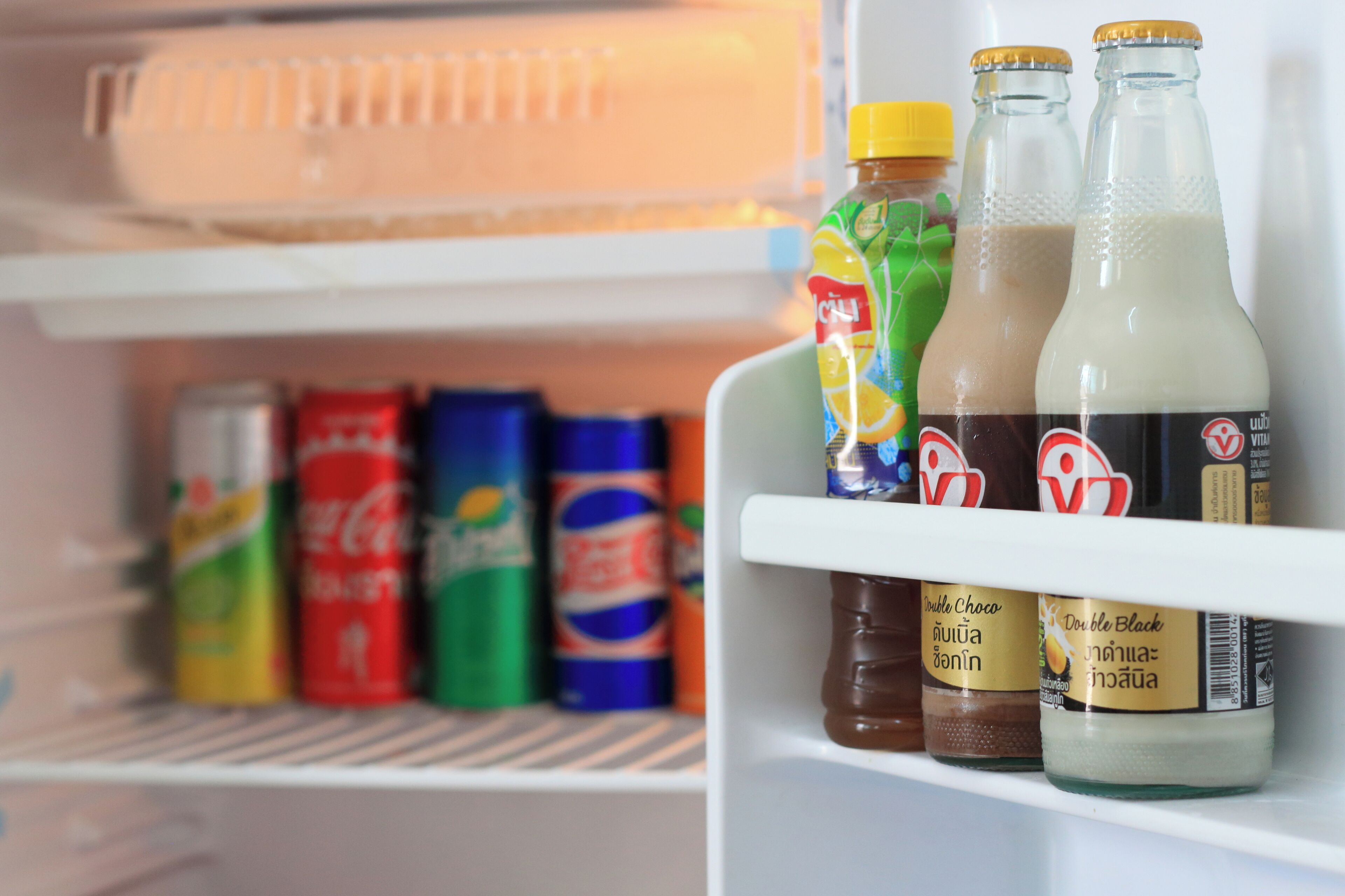 Una estantería de refrigerador con diversas bebidas, incluyendo una botella de leche, una botella de jugo y una botella de refresco.