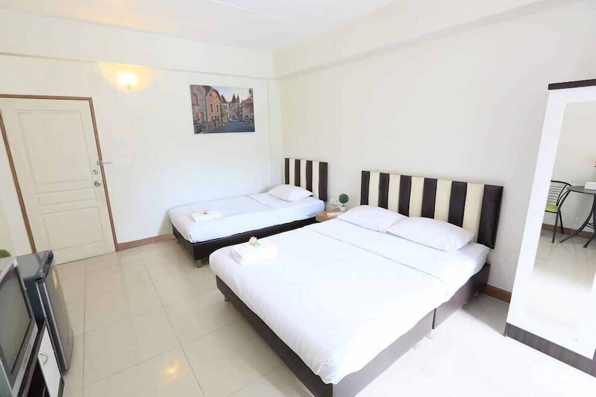 A hotel room with two beds, a door, a painting, and a desk with a chair.