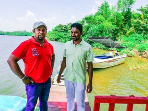 Two men standing on a dock by a body of water with a boat nearby. - Mahi Villa (Bentota)