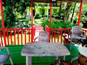 A covered outdoor seating area with a table and chairs, surrounded by a red railing and greenery. - Mahi Villa (Bentota)