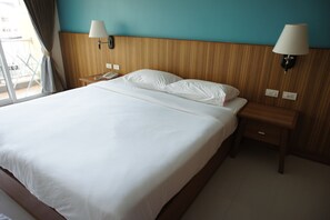 A hotel room with a large bed, two bedside lamps, a nightstand, and a window with curtains.