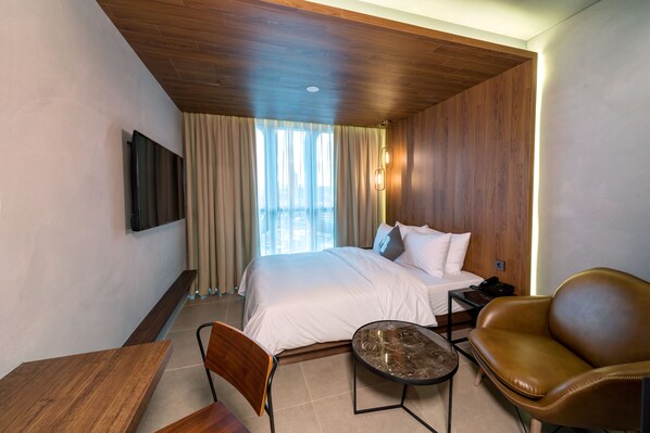 A hotel room with a bed, a desk, a chair, a leather sofa, a small table, and a TV mounted on the wall. - Hotel the Designers DDP (Seoul)