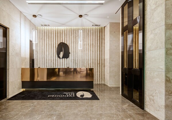 A hotel reception area with a modern design, featuring a reception desk, a black and gold reception area, and a reception desk mat with the hotel's name.