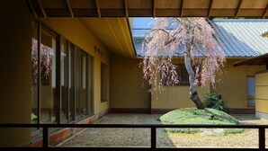 A traditional Japanese building with a view of a cherry blossom tree and a small rock garden. - Saryou Souen (Sendai)