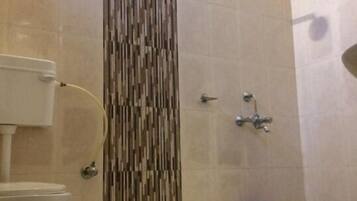 A bathroom with a toilet, a shower, and a blue bucket.