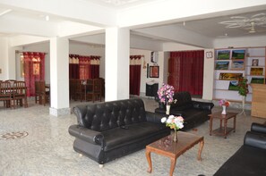 Un salón amplio con un sofá de cuero negro, una mesa de centro de madera y un comedor con sillas y mesa de madera.