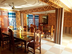 Un comedor con mesa de vidrio, sillas de madera y cortinas con diseño.
