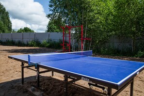 A ping pong table set up outdoors with a metal fence and trees in the background. - Nikitskoe podvorie (Maurino)