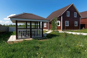 A residential area with a wooden house, a covered outdoor seating area, and a well-maintained garden. - Nikitskoe podvorie (Maurino)