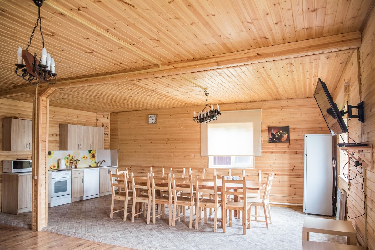 A wooden interior with a dining area, kitchen, and a large window.