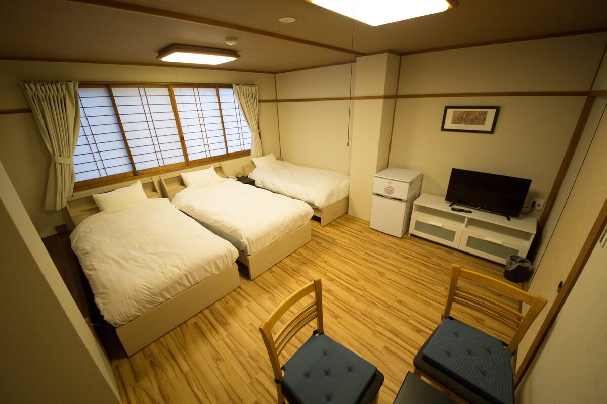 A room with two beds, a TV, and a small table.