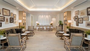 Eine geräumige Lobby mit einer zentralen Rezeption, flankiert von Sitzbereichen mit gepolsterten Sesseln und Tischen.