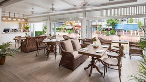 Ein offenes Restaurant mit Korbmöbeln, großen Fenstern und Blick auf den Außenbereich.