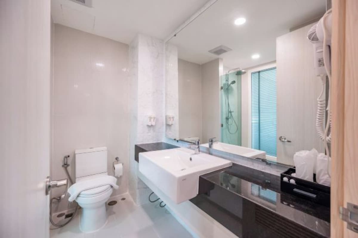 A modern bathroom with a large sink, mirror, and shower.