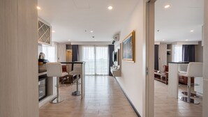 Una camera d'albergo moderna con angolo cottura, zona pranzo e un'ampia finestra con tende.
