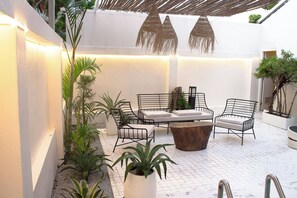 A patio area with a seating arrangement, including a table and chairs, surrounded by potted plants and a pergola structure. - Sonia Residence (Pattaya)