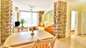 A dining area with a round table and chairs, a television, and a plant. - Family Hotel Sirena Palace (Obzor)