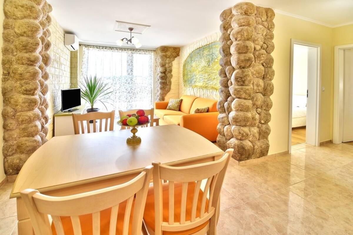 Un coin repas avec une table ronde et des chaises, un téléviseur et une plante.