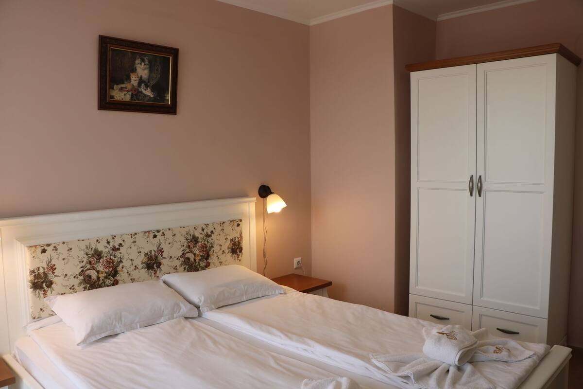 Une chambre à coucher avec un lit, une table de chevet, une lampe, une armoire et un tableau au mur.