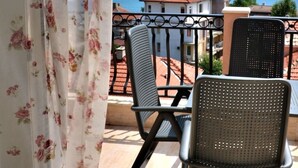 A balcony with two chairs and a table, overlooking a coastal view with buildings and a clear sky. - Family Hotel Sirena Palace (Obzor)