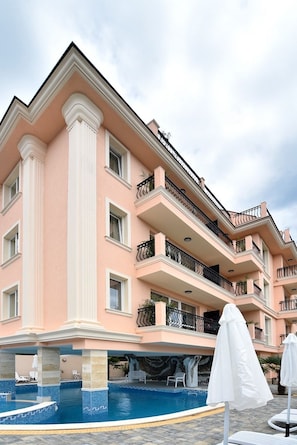 A multi-story hotel with balconies, a swimming pool, and outdoor seating.