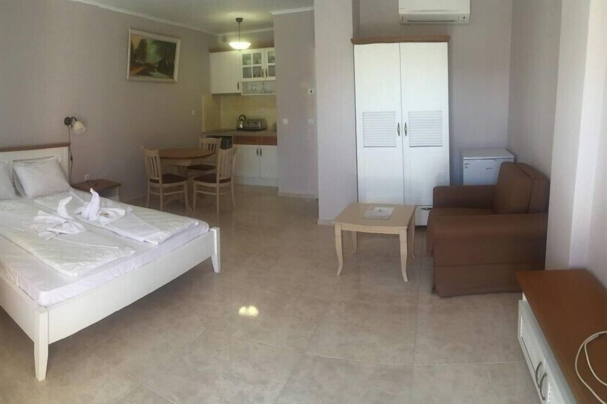 Une chambre d’hôtel comprenant un lit, une petite table, un canapé, un coin cuisine et une armoire.