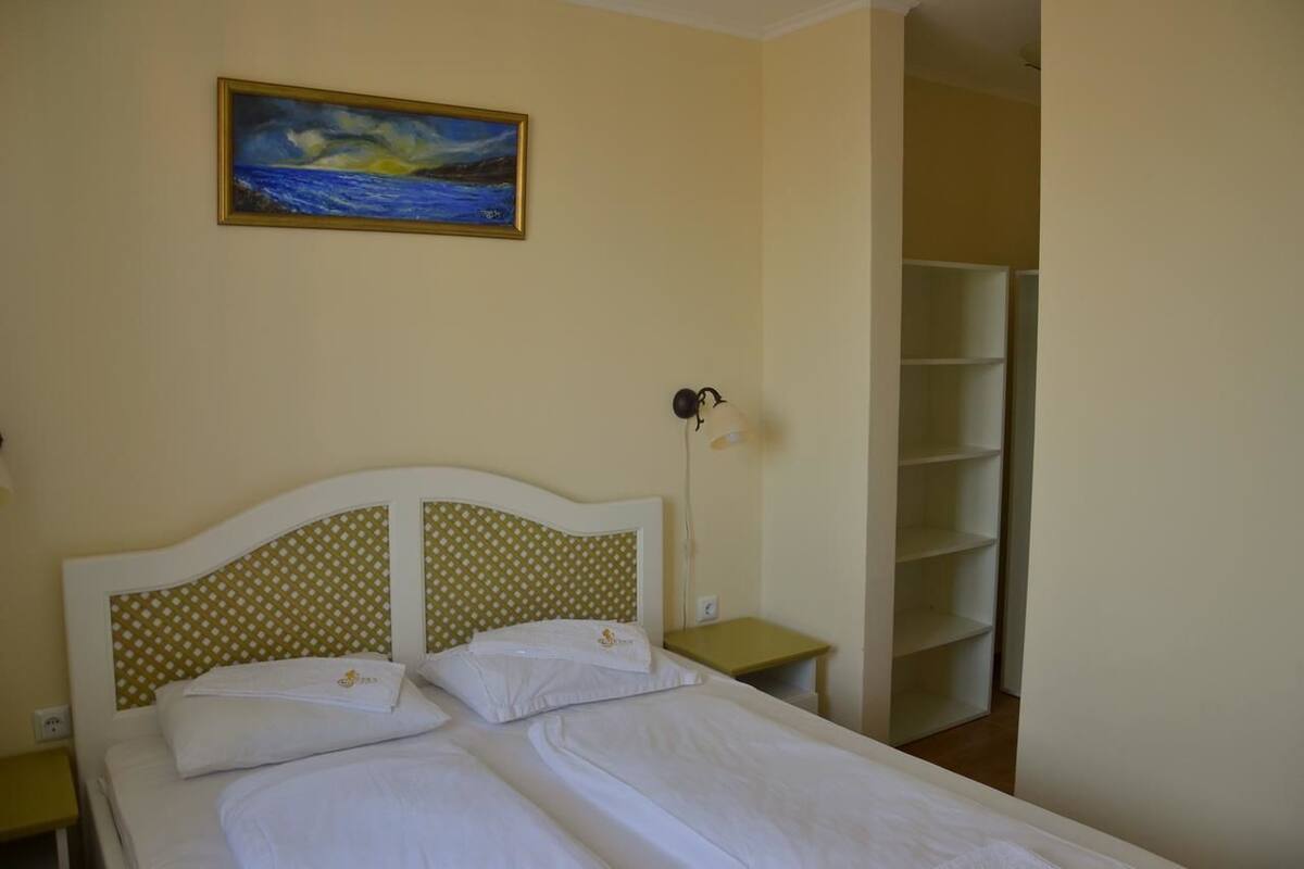 Un lit double avec une tête de lit à motifs, une table de chevet avec une lampe et un tableau accroché au mur.