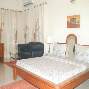 Un dormitorio con cama, sofá, lámpara y cortinas con diseño de jirafa.