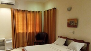 Une chambre d’hôtel avec un lit, une chaise, un bureau et un téléphone fixé au mur.