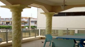 Un balcon avec une table et des chaises, de grandes colonnes et une vue sur les bâtiments en arrière-plan.