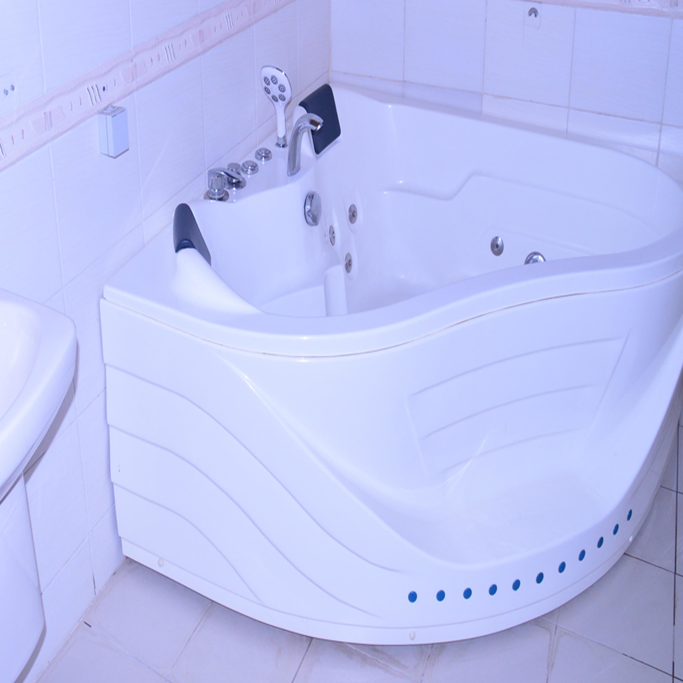 Eine weiße Badewanne mit geschwungener Form, einer Duschbrause und einer Bedienkonsole.